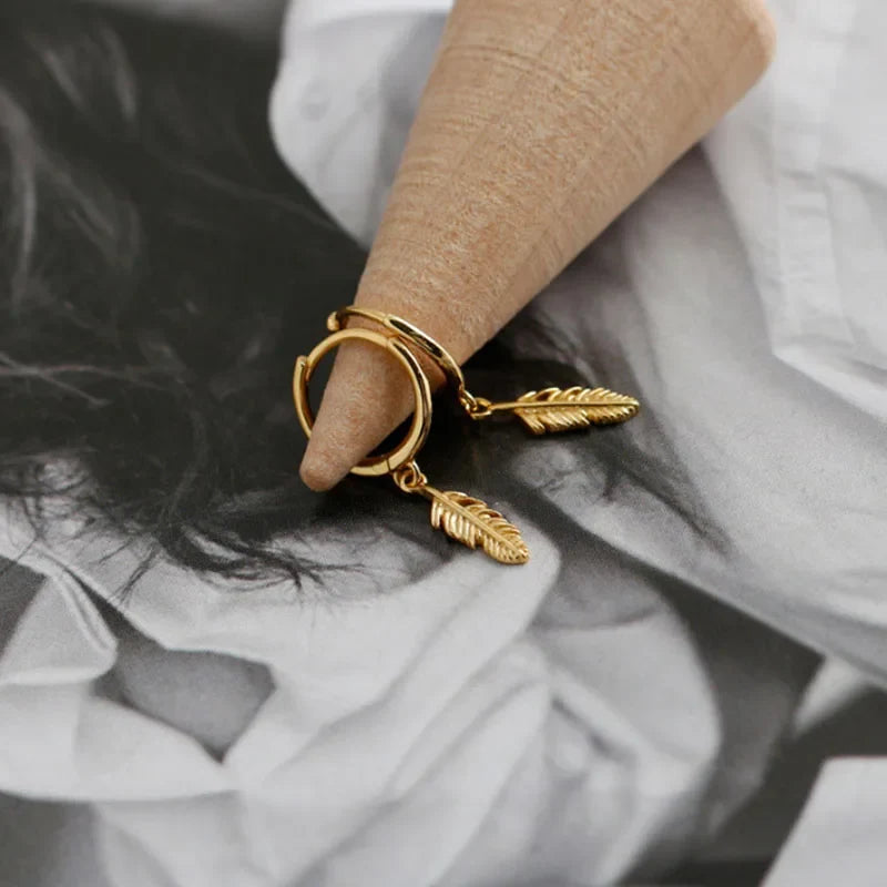 Gold hoop earrings with a small dangling feather