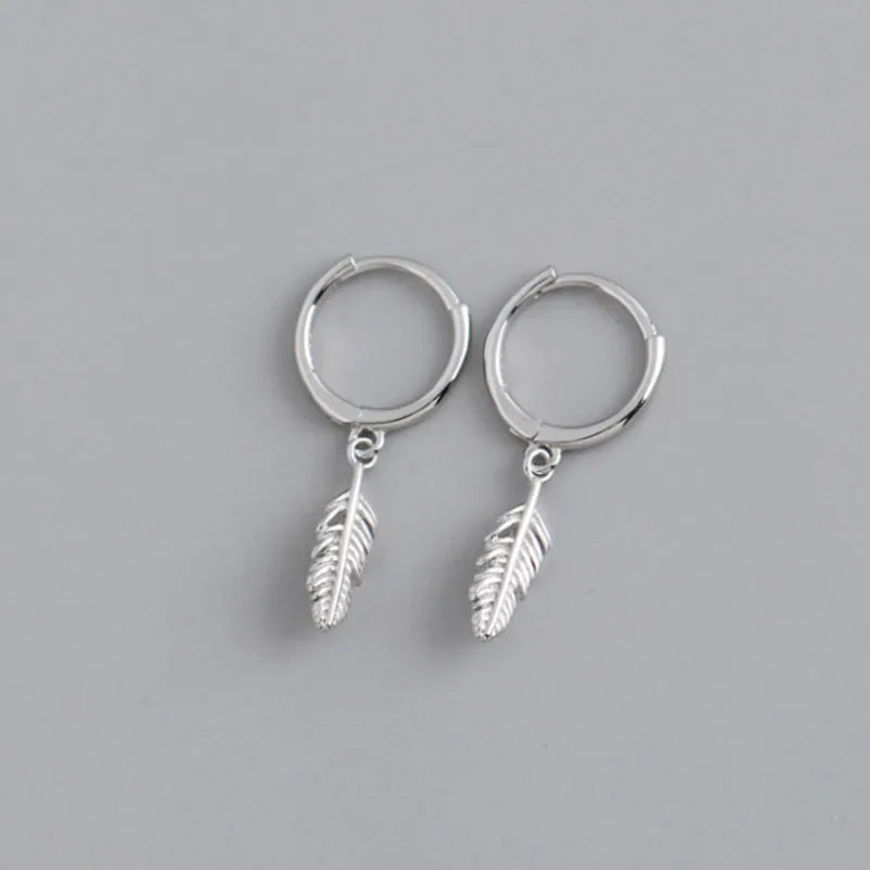 Silver hoop earrings with a small dangling feather