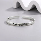 Open bangle bracelet with silver-tone feather