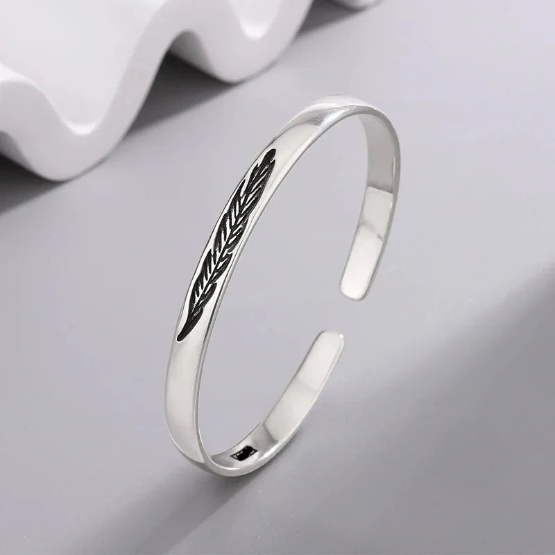 Open bangle bracelet with silver-tone feather