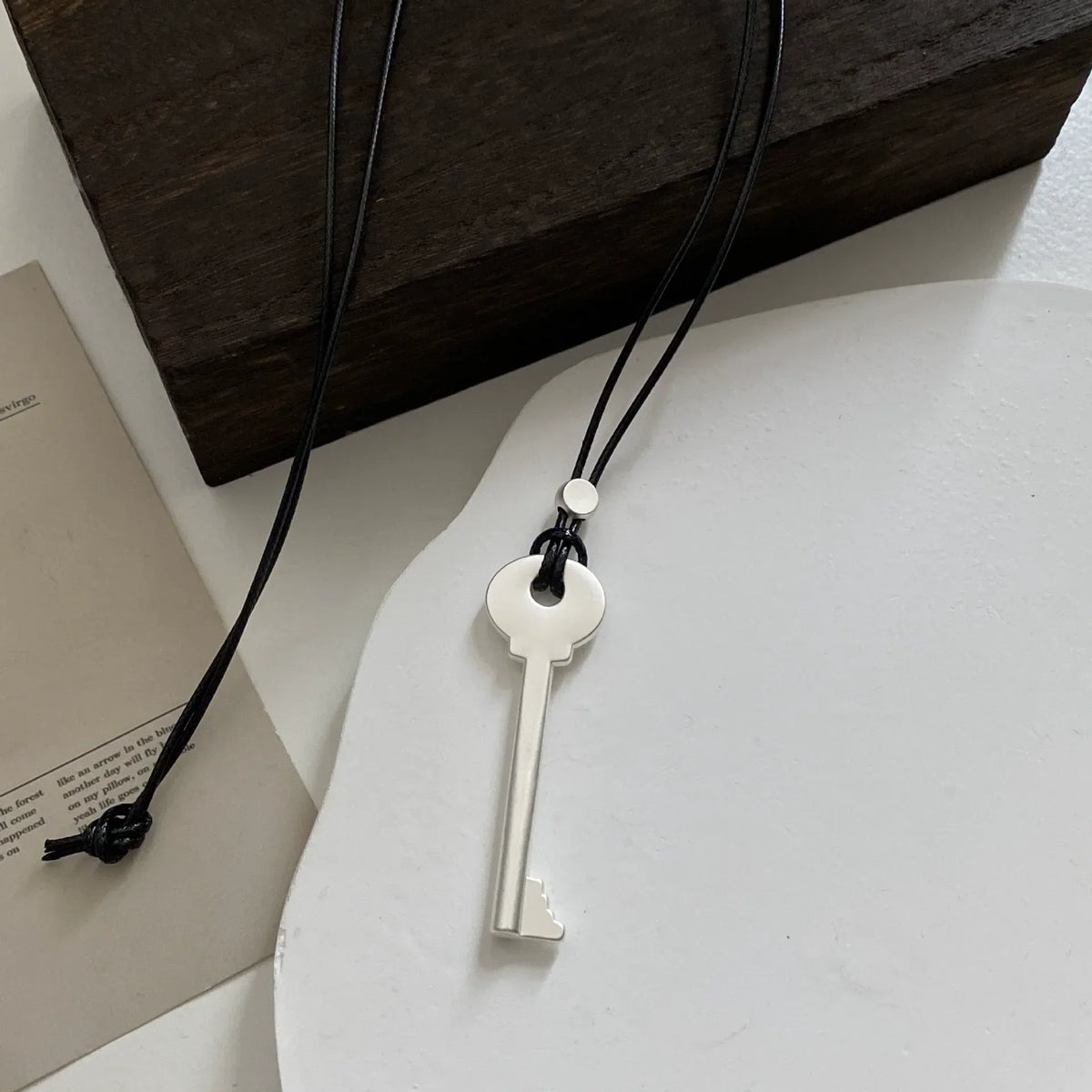 Long cord necklace with matte silver key pendant